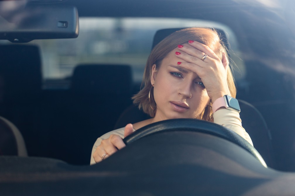 woman sitting her car looking frustrated as it vibrates while in idle position